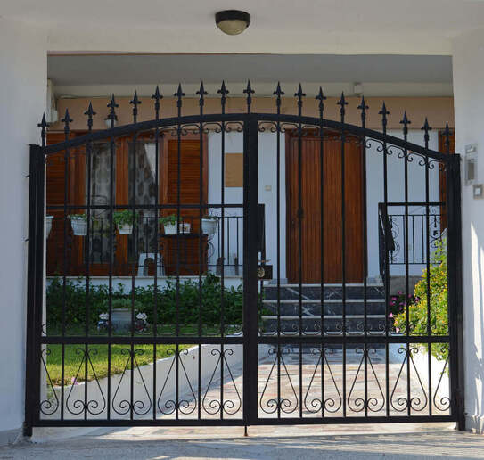 a stell automatic gate with a house in the background